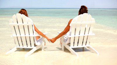stock-footage-rear-view-of-romantic-couple-holding-hands-while-sitting-on-deck-chairs-at-seashore
